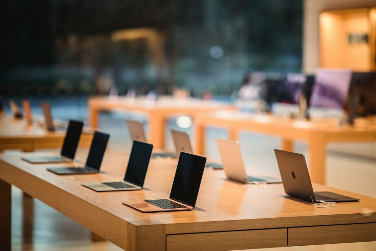Laptops lined up on a display table at an apple store
