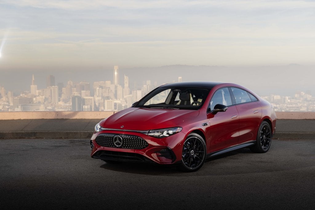 Official Mercedes-Benz electric CLA 250+ launch image: front three-quarter view in Patagonia Red with the San Francisco skyline behind it