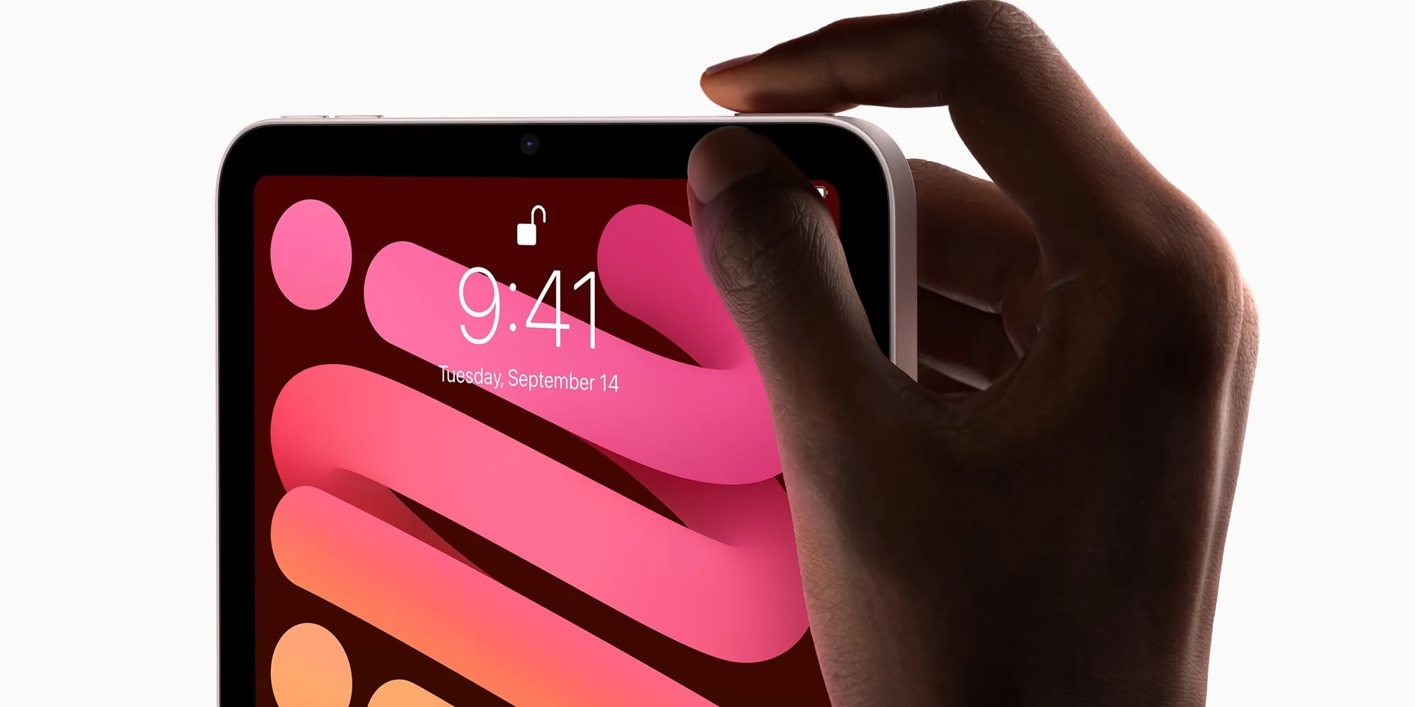 Apple iPad mini held in one hand, showing the Touch ID power button on the top edge