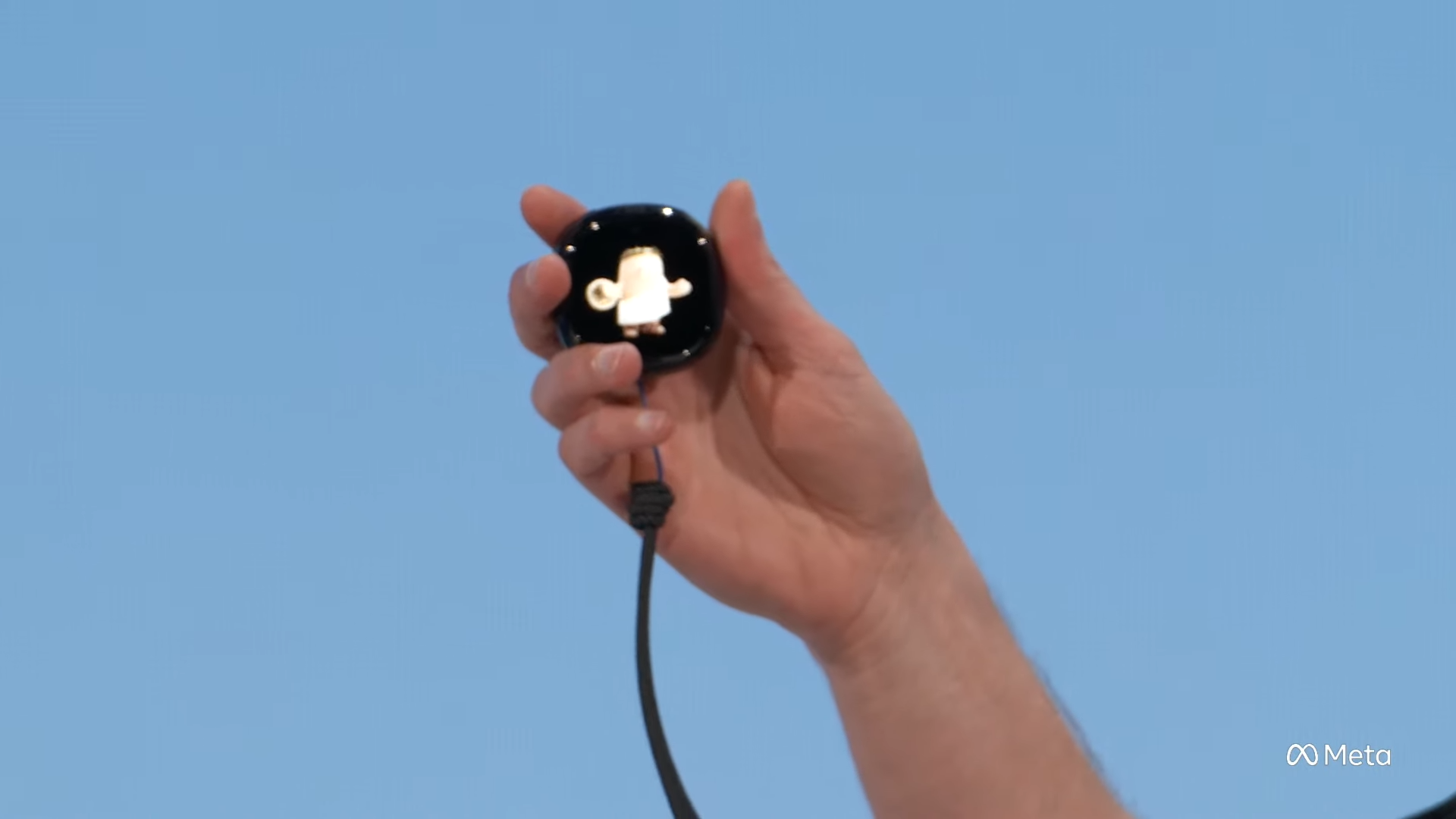 Mark Zuckerberg holds up Muse Charm, a small black puck on a cord with a screen showing his toga-wearing Muse avatar, at Meta Connect 2026