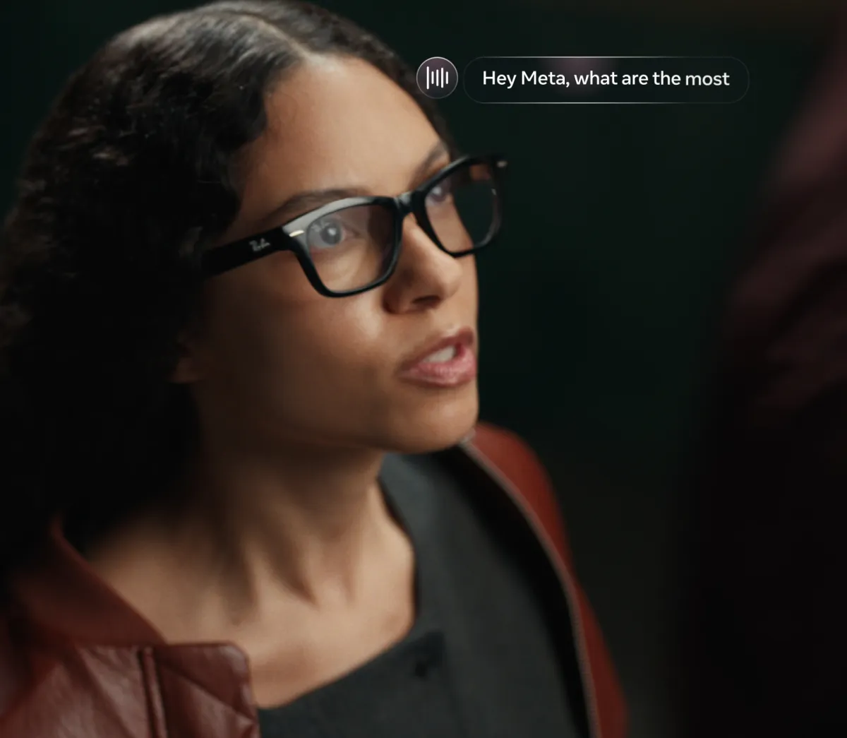 A woman wearing black rectangular Ray-Ban Meta Audio glasses, which have no camera, asking Meta AI a question