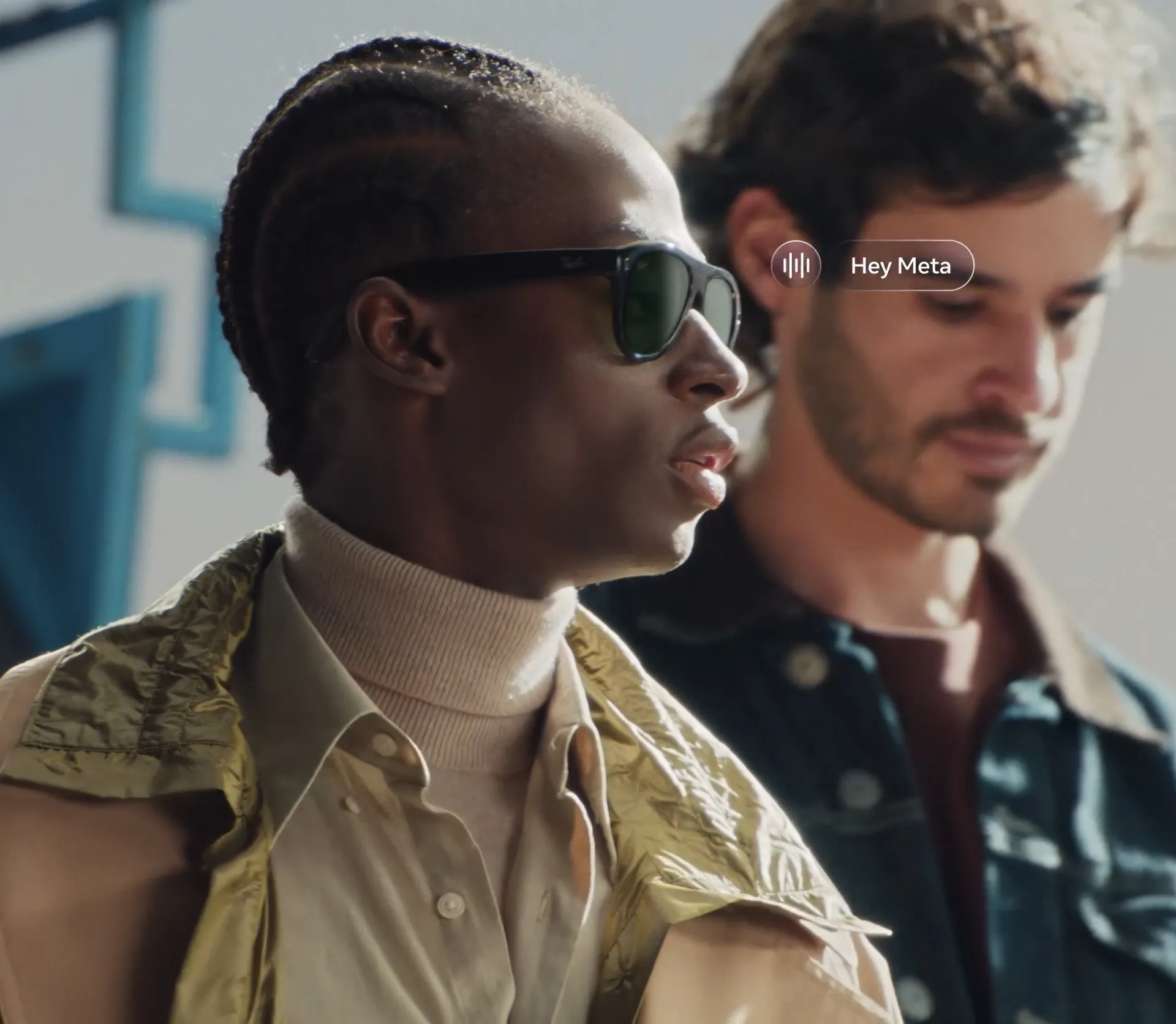 A man wearing Ray-Ban Meta Gen 3 smart glasses with dark green lenses, with a Hey Meta voice prompt shown beside him