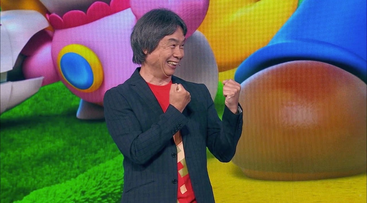 Shigeru Miyamoto standing onstage, speaking into a microphone