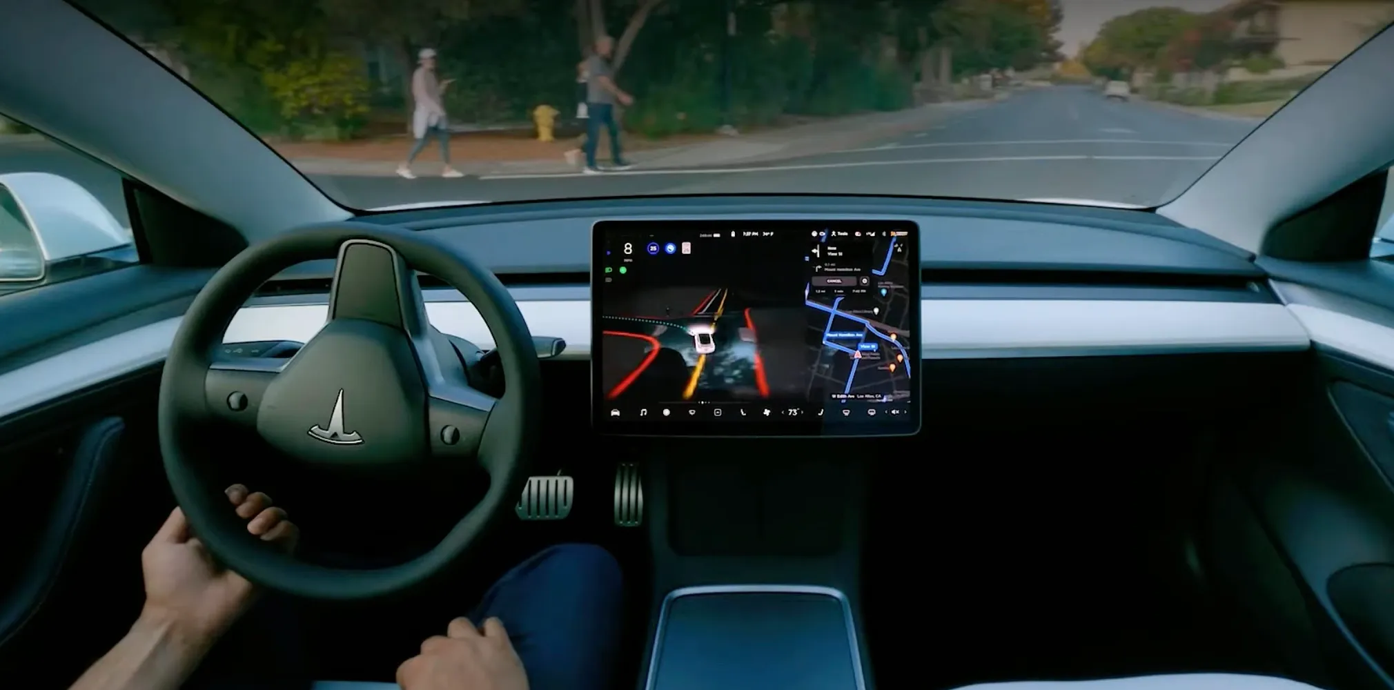 Tesla steering wheel and touchscreen from the driver's seat, showing the Full Self-Driving visualization while the car is on the road